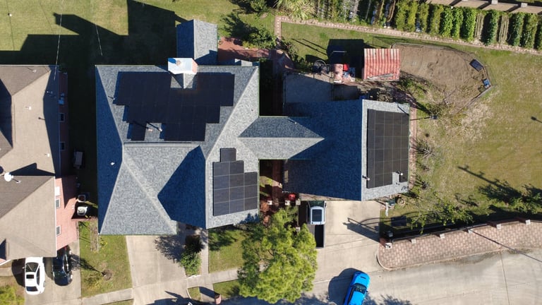 Aerial view of a residential house with blue roof and solar panels installed on top