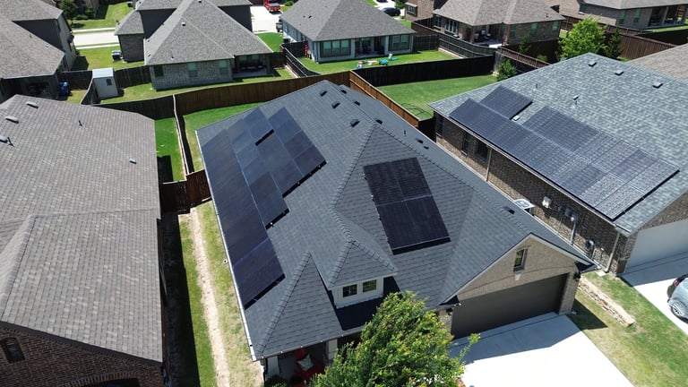 Aerial view of residential home with solar panels installed on dark roof in suburban neighborhood