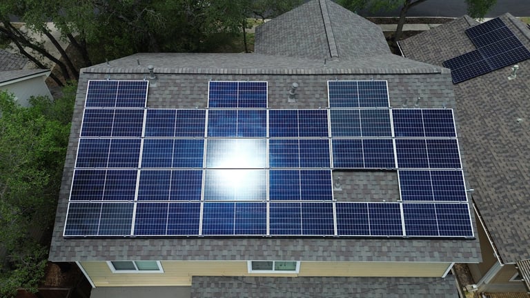 Aerial view of a residential roof with a solar panel array installed, featuring blue photovoltaic panels in a 3x6 grid arrangement