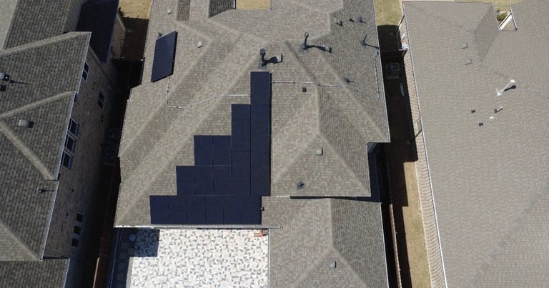 Aerial view of buildings casting dark shadows on a concrete plaza with scattered seating areas