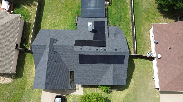 Aerial view of a two-story house with gray roof surrounded by green lawn and neighboring properties