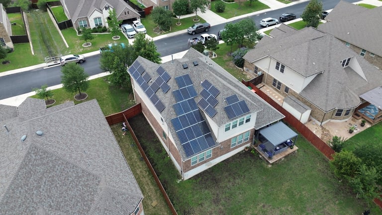 Aerial view of residential house with solar panels on roof, suburban neighborhood with green yards and parked cars