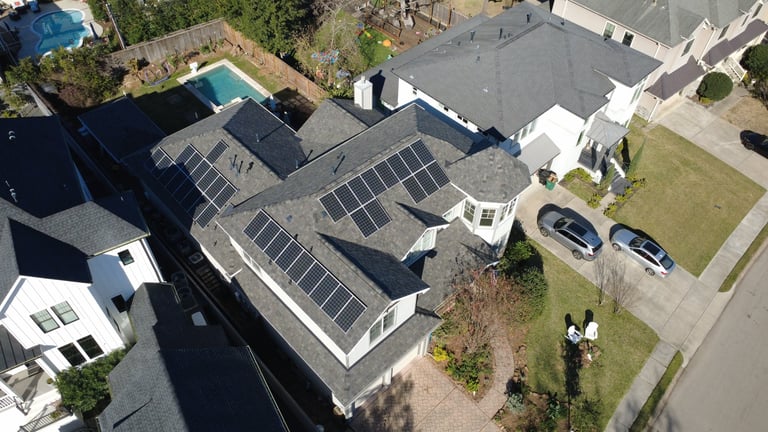 Aerial view of residential houses with solar panels installed on roofs in a suburban neighborhood
