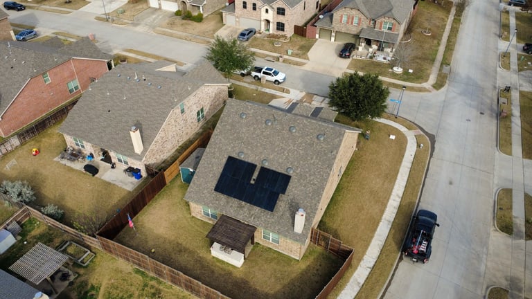 Aerial view of residential homes with solar panels on roof in suburban neighborhood