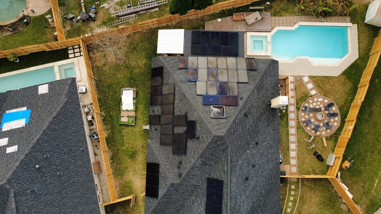 Aerial view of a residential property with dark-shingled roof, swimming pool, and manicured landscaping