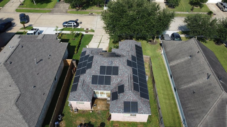 Aerial view of residential house with solar panels installed on roof, surrounded by other homes and trees in suburban neighborhood