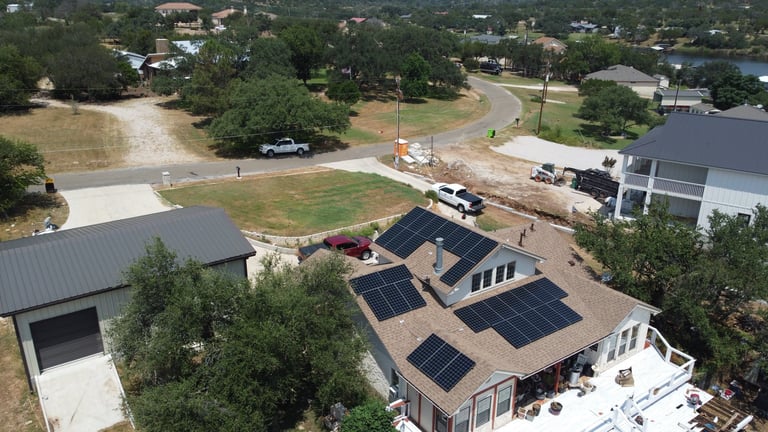 Aerial view of residential property with solar panels on roof and surrounding rural landscape with trees and buildings