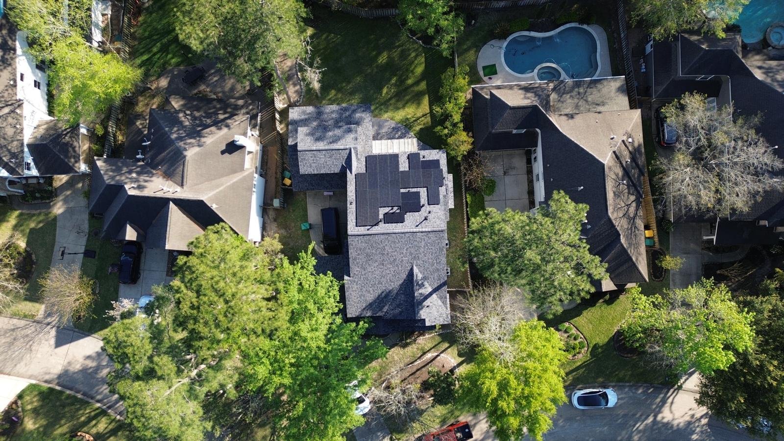 Aerial view of residential neighborhood with houses, trees, and a backyard swimming pool