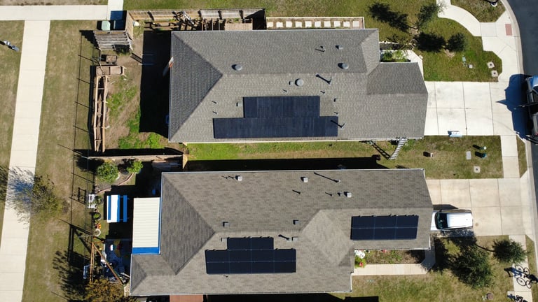 Aerial view of two residential houses with solar panel installations on their roofs and driveways
